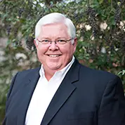 A man with white hair and glasses in a suit.